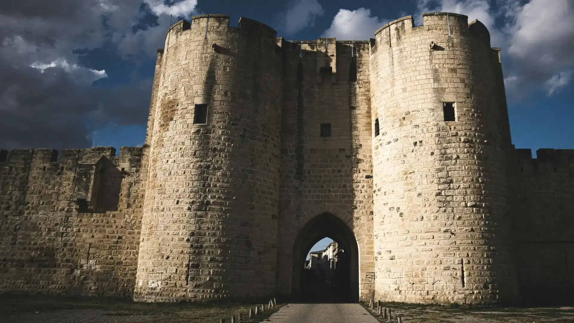 A twin-towered gateway in the medieval ramparts of Aigues-Mortes, its pointed arch opening onto a street inside the walls